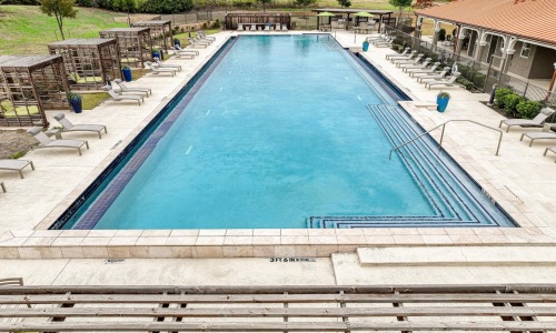 a swimming pool with a deck and chairs around it
